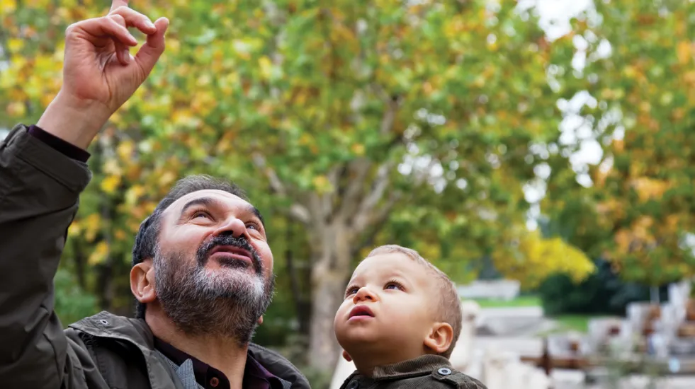 Jewish grandfather holding child and point to the sky
