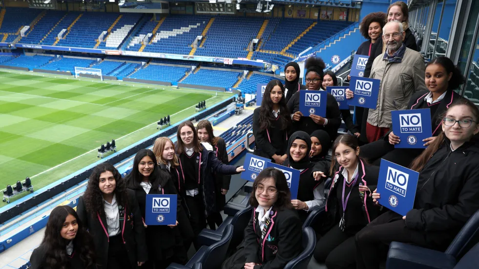 Students in a football stadium holding signs that read "No to Hate"