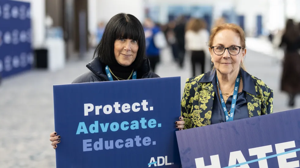 Females holding signs "Protect.Advocate.Educate" and "No Hate" at ADL Never Is Now