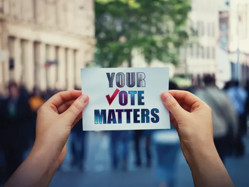 Hands hold a piece of paper with the message "Your Vote Matters"