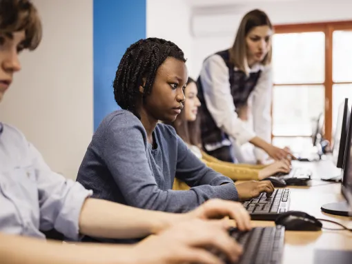 Teacher assisting high school students using computers in a computer lab
