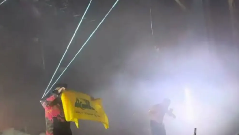 Kneecap band member holding up a Hezbollah flag, November 2024 concert