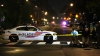 A police car and crime scene tape block off a street at night.